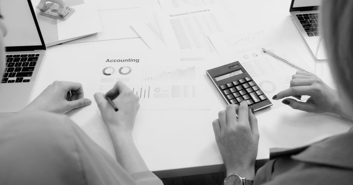 Manos con calculadora y gráficos impresos de contabilidad, en blanco y negro