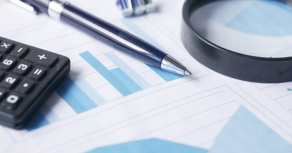 Lupa, calculadora y bolígrafo sobre documentos de auditoría