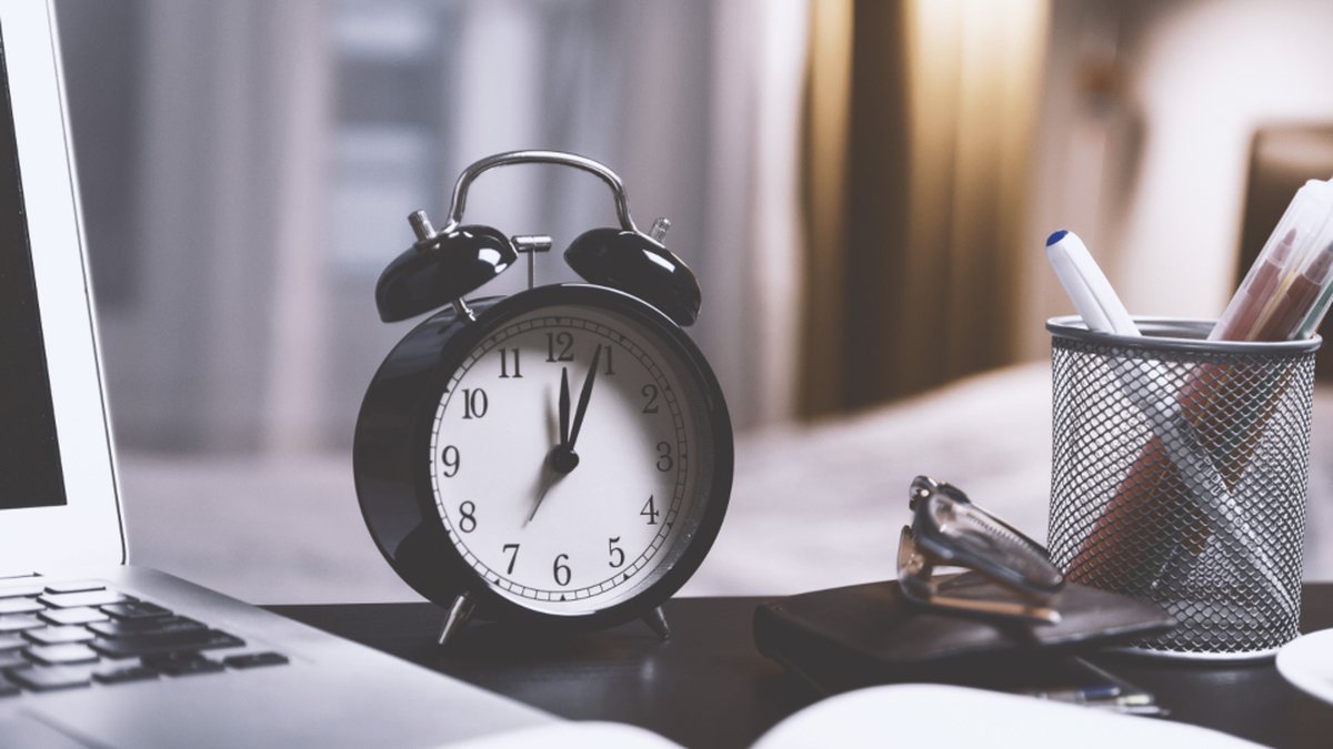 Reloj despertador clásico junto a un portátil