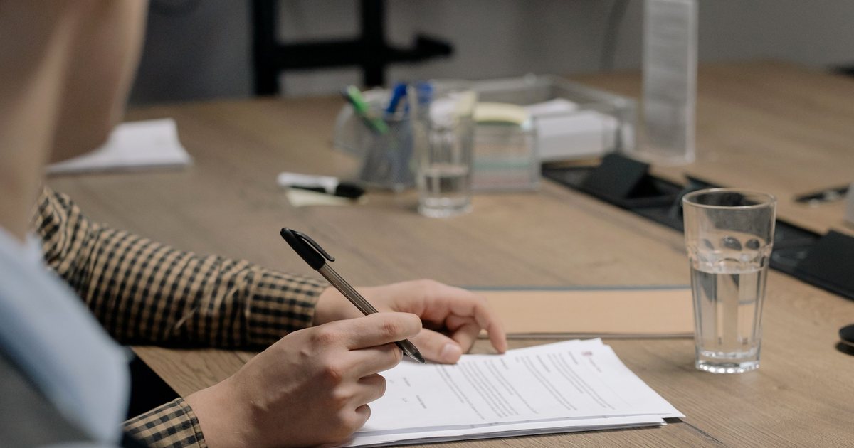Mano firmando un documento en una mesa de reunión