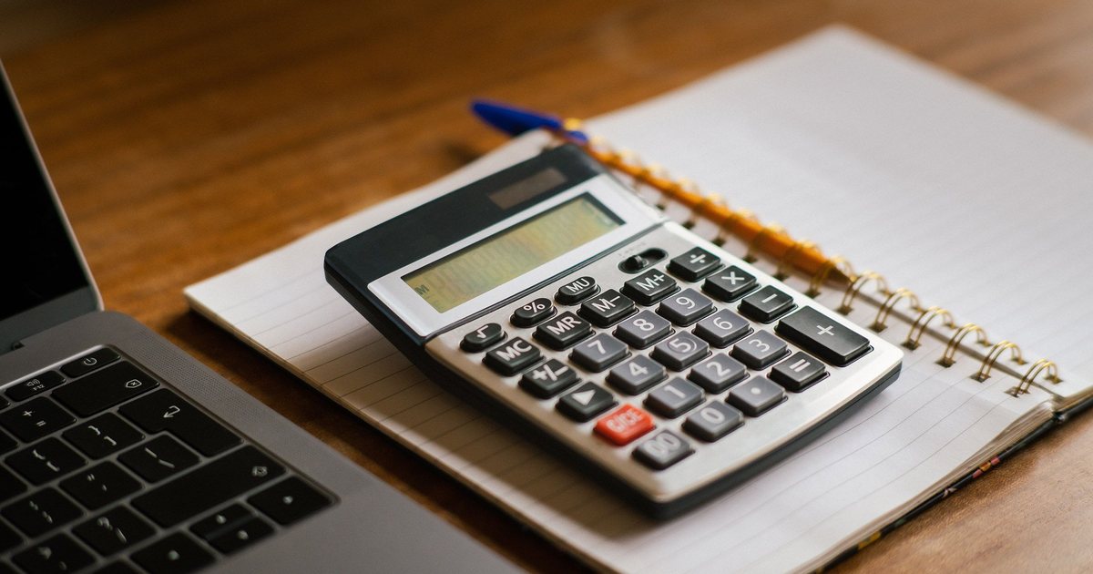 Calculadora sobre un cuaderno junto a un portátil