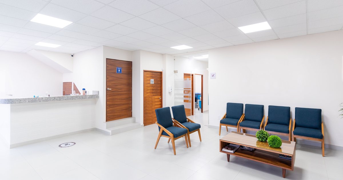 Sala de espera vacía de una clínica con sillas y mostrador