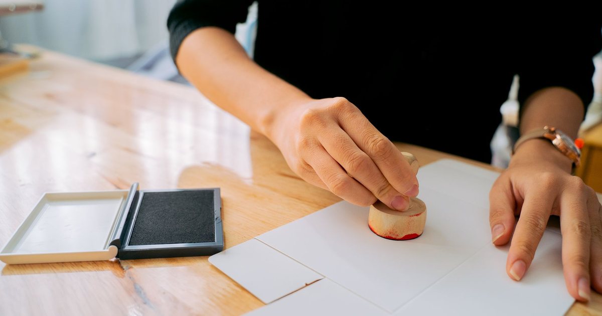 Mano sellando un documento oficial sobre la mesa