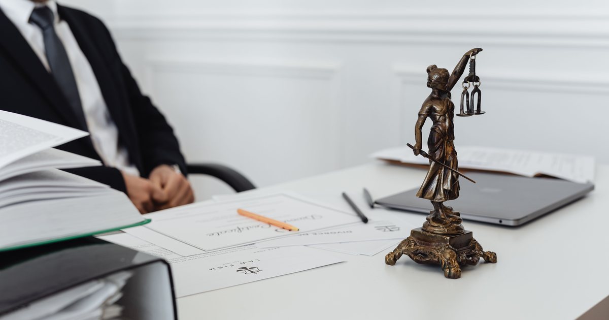 Documentos apilados junto a una figura de la justicia sobre una mesa