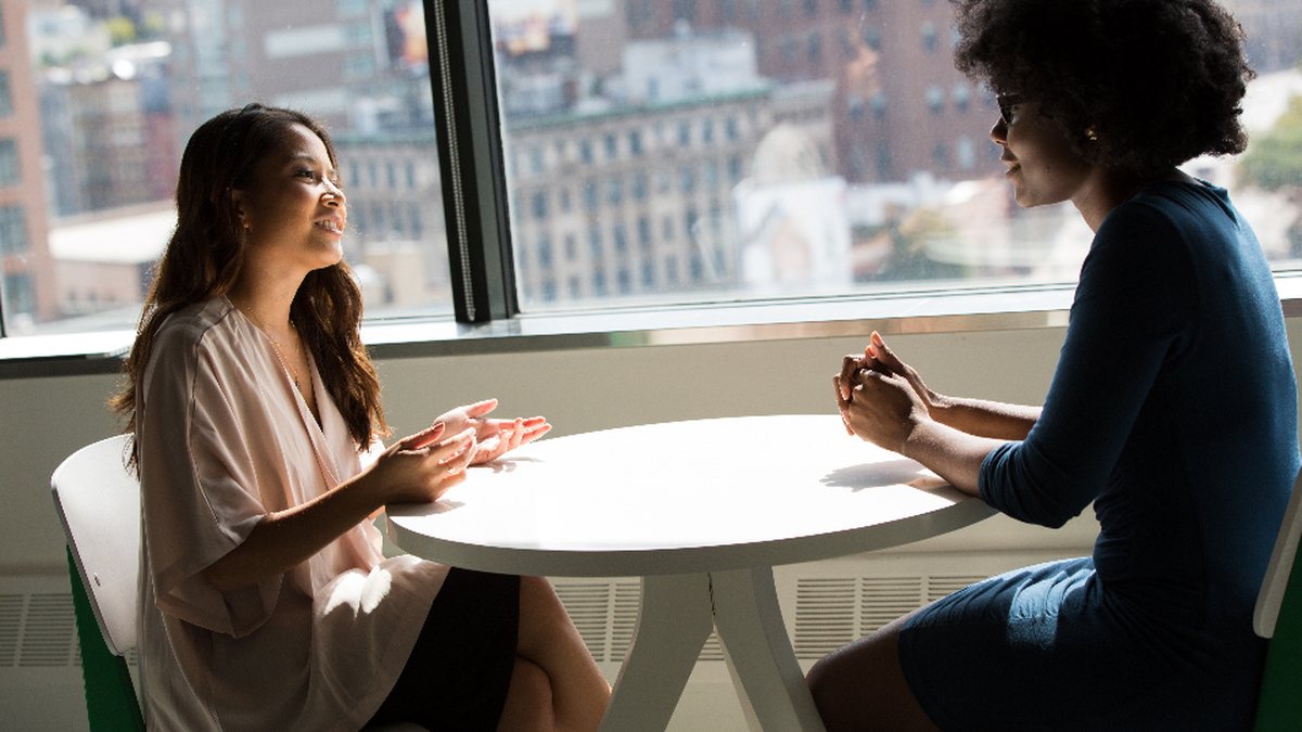 Deux professionnelles discutant à une table avec vue sur la ville