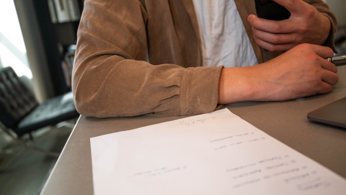 Persona revisando un documento firmado junto a un teléfono móvil