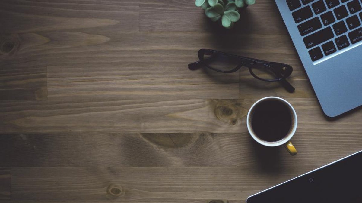 Vista cenital de un escritorio con café, gafas y un portátil