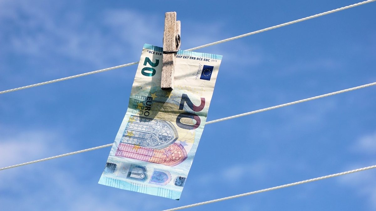 Billete de euro tendido con una pinza de la ropa contra el cielo
