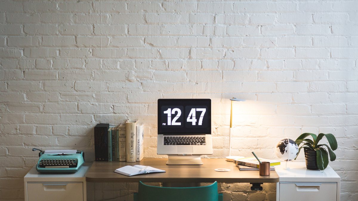 Reloj digital de escritorio marcando la hora junto a una máquina de escribir