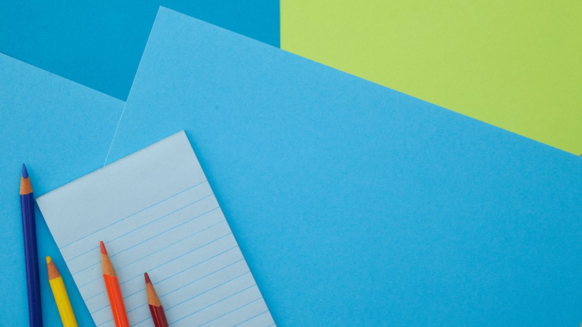 Lápices de colores y una libreta sobre un fondo azul