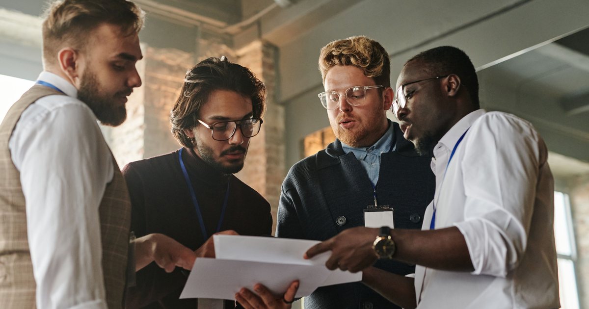 Equipo de profesionales revisando un documento de pie durante una reunión