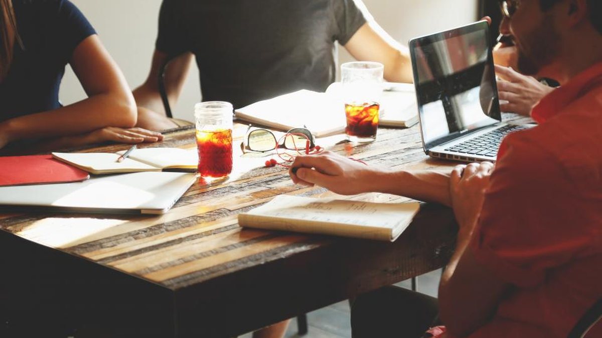 Grupo de personas trabajando junto a una mesa con portátiles y cuadernos