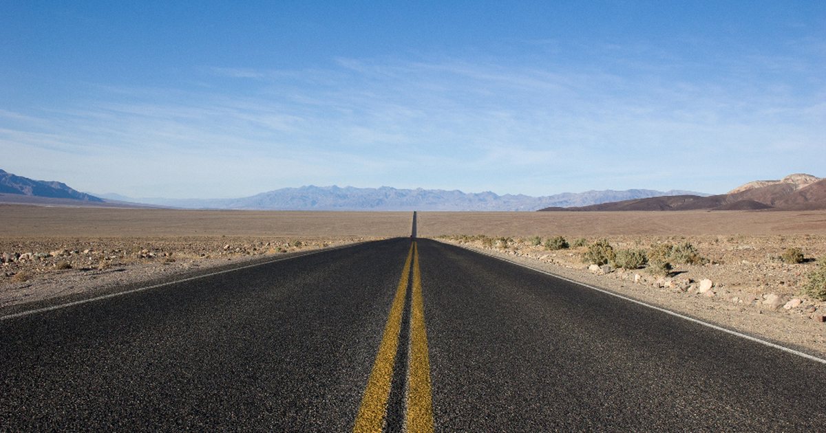 Carretera recta vacía atravesando un paisaje desértico bajo un cielo despejado