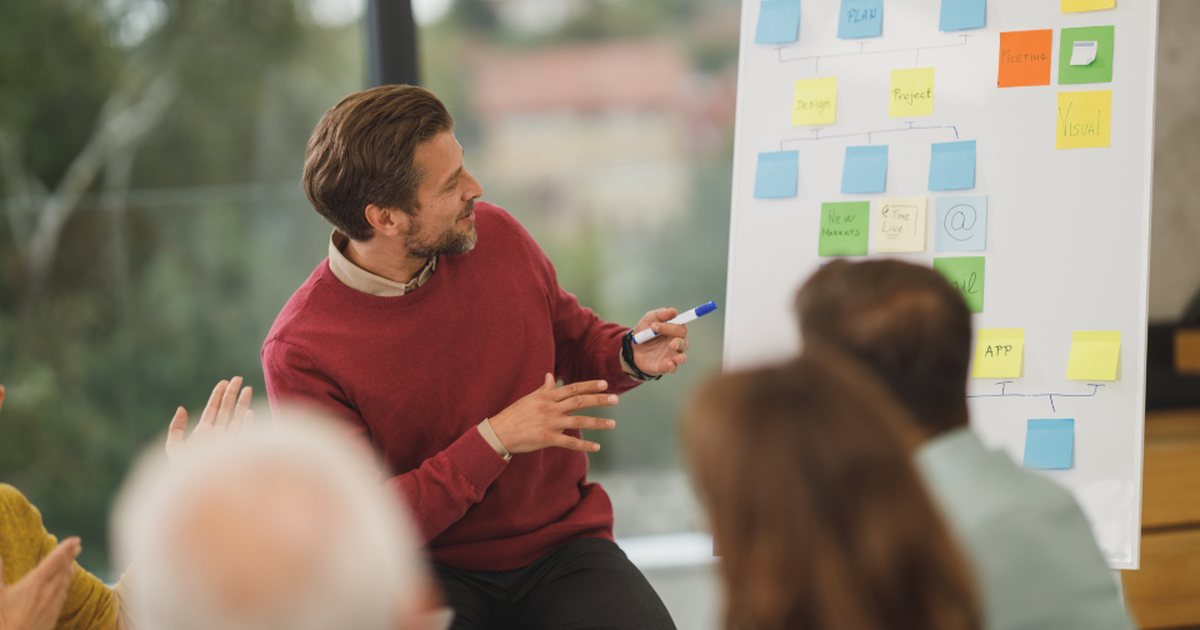 Persona presentando ideas con notas adhesivas ante un grupo de compañeros
