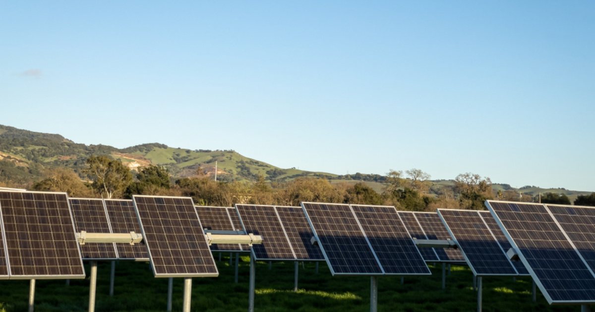 Placas solares fotovoltaicas instaladas en un terreno con colinas al fondo